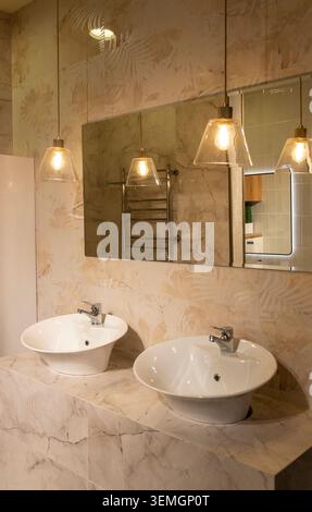 Bagno dal design contemporaneo con eleganti luci sospese e doppio lavabo Foto Stock