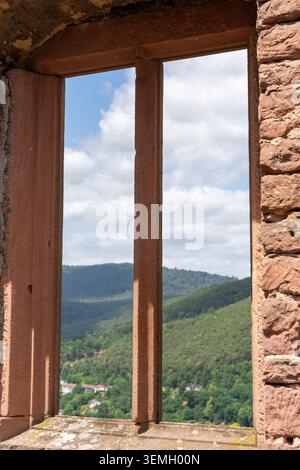 Una vista attraverso una finestra di arenaria delle rovine del monastero di Limburgo che si affacciano sulle verdi colline boscose, sulle case sparse e sulle morbide nuvole vicino a Bad Dürkheim Foto Stock