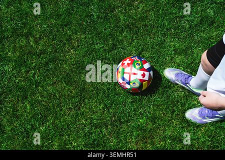 I piedi del giocatore di calcio calpestano il pallone da calcio per il calcio d'inizio nello stadio Foto Stock