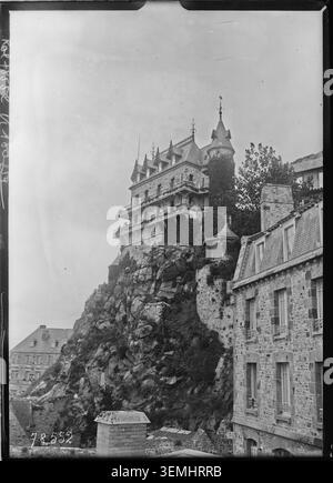Una fotografia stampa di Agence Rol del 1922 presenta una vista dell'Abbazia di Mont-Saint-Michel in Normandia. L'immagine monocromatica registra l'abbazia medievale che si erge sopra il sito dell'isola e faceva parte di una serie di documentazione della stampa francese. Foto Stock
