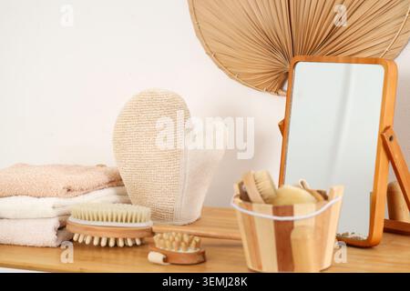 Guanto massaggiante con spazzole e specchio sullo scaffale in bagno Foto Stock