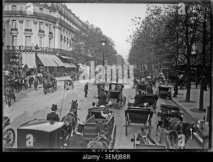 Il traffico scorre lungo Boulevard des Capucines a Parigi nel 1906 mentre veicoli trainati da cavalli e automobili viaggiano insieme. La fotografia della stampa registra la circolazione urbana e il cambio di trasporto nella capitale francese durante il periodo della Belle Époque. Foto Stock