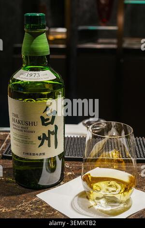 Tokyo, Giappone – 1 settembre 2025: Una bottiglia di whisky giapponese single malt The Hakushu esposta accanto a un bicchiere di whisky versato su un bancone del bar. Foto Stock