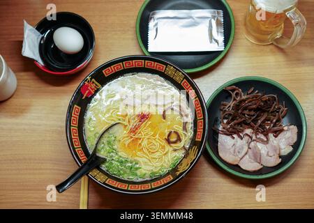 Tokyo, Giappone – 30 agosto 2025: Ramen tonkatsu Ichiran con uovo sodo, maiale a fette, funghi orecchie di legno e birra a Shibuya. Foto Stock