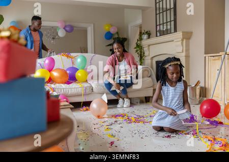 Famiglia afroamericana che ospita a casa, ragazza che gestisce l'arredamento di feste, donna che legge carte, copia spazio Foto Stock