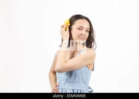 Bella giovane donna che applica crema cosmetica sulla sua guancia morbida Foto Stock