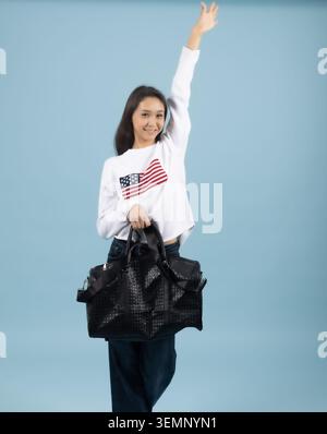 Giovane donna eccitata che tiene in mano borse della spesa di carta nera dopo la vendita Foto Stock