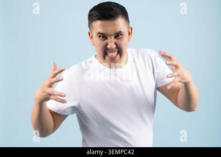 Giovane che urla furiosamente con le mani diffonde una minaccia aperta e aggressiva Foto Stock