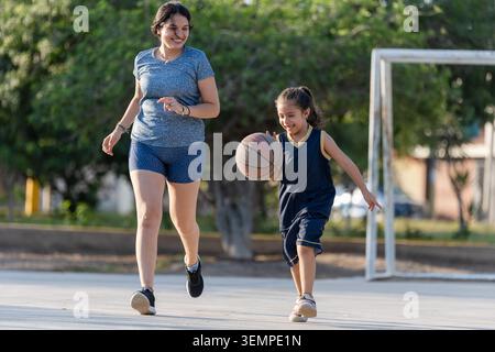Madre e figlia felici che giocano a basket all'aperto Foto Stock