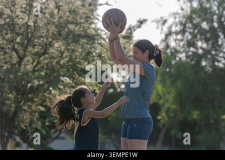 Madre e figlia giocano a basket all'aperto Foto Stock