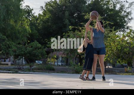 Madre e figlia giocano a basket all'aperto insieme Foto Stock