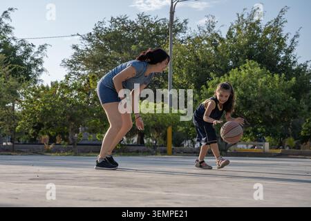 Madre e figlia giocano a basket all'aperto Foto Stock