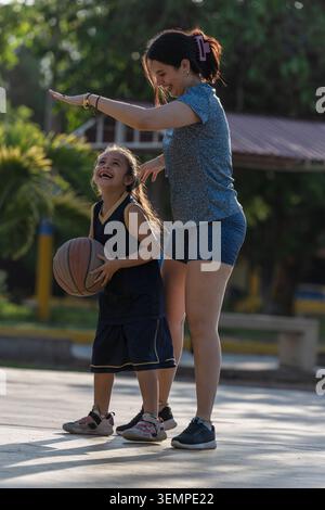 Madre e figlia felici che giocano a basket all'aperto Foto Stock