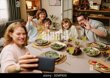 La famiglia scatta foto sullo smartphone durante il pranzo domenicale a casa Foto Stock