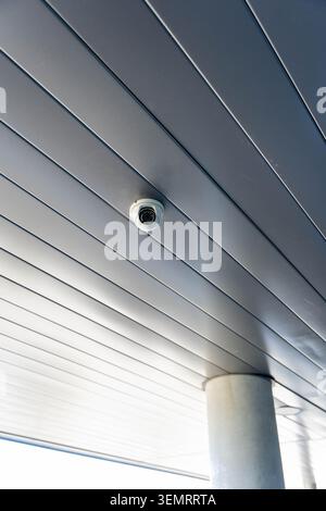 Telecamera di sicurezza montata su un soffitto moderno che crea un senso di sorveglianza Foto Stock