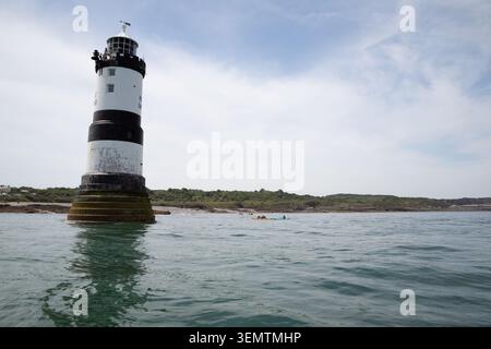 Kayak nei pressi del faro di Trwyn du / Penmon visto dall'acqua - preso in una giornata tranquilla sullo stretto di menai Foto Stock