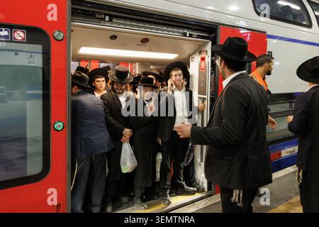 Ebrei Haredi ultra-ortodossi che salgono su un affollato treno pendolare alla stazione ferroviaria di Gerusalemme, Israele Foto Stock
