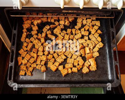 vista dall'alto delle fette di pane di segale tagliate a cubetti sul vassoio del forno nella cucina rurale Foto Stock