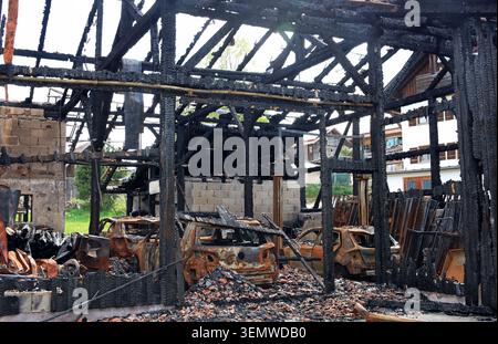 Dopo un incendio in un garage, tutto ciò che rimane è un'auto bruciata e fasci carbonizzati Foto Stock