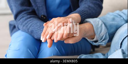 Operatore sanitario che tiene la mano del paziente anziano, fornisce comfort e supporto, cure mediche e compassione Foto Stock