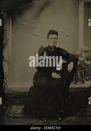 Questa immagine mostra un'antica fotografia in tintype della fine degli anni '1800, raffigurante una donna con un abito scuro di epoca vittoriana. Foto Stock