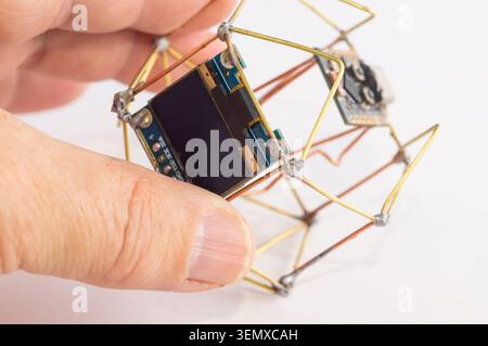 Primo piano di un orologio decorativo fatto a mano tenuto in mano. Foto Stock