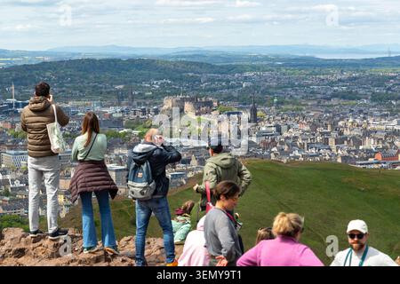 Persone che ammirano il panorama della città di Edimburgo e del Castello di Edimburgo dalla cima di Arthurs Seat, Holyrood Park, Edimburgo. Foto Stock