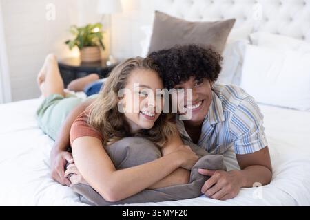 Diverse coppie sdraiate sul letto in una luminosa camera da letto, riposate su un morbido cuscino grigio Foto Stock
