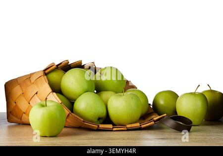 Mele verdi mature fresche nel tradizionale cestello di vimini su un tavolo di legno isolato su sfondo bianco. Frutta biologica sana con spazio di copia. Foto Stock