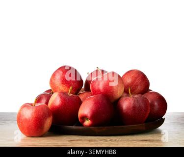 Mele rosse mature fresche disposte su un piatto di legno su un tavolo di legno isolato su fondo bianco. Frutta biologica sana con spazio di copia. Foto Stock