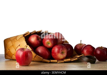Mele rosse mature fresche nel tradizionale cestino di vimini su un tavolo di legno isolato su sfondo bianco. Frutta biologica sana con spazio di copia. Foto Stock