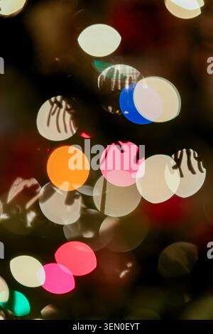 Luci bokeh astratte colorate che creano un'atmosfera festosa e vibrante nel buio. Foto Stock