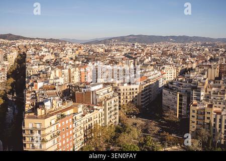 Vista aerea di una città densamente piena di edifici sotto un cielo azzurro e montagne sullo sfondo. Foto Stock