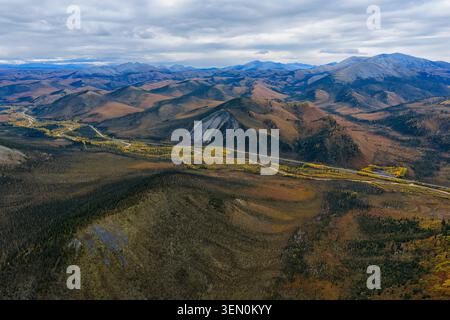 Vista aerea di vasti paesaggi montani con strade tortuose sotto un cielo nuvoloso. Foto Stock