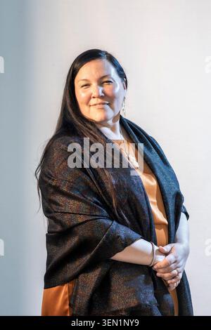 Una donna sta con le mani unite davanti a lei. Indossa uno scialle e un vestito in uno spazio interno luminoso. La luce riempie lo sfondo, evidenziandolo Foto Stock