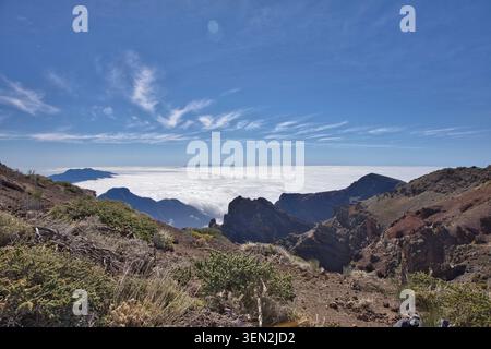 Vista mozzafiato di un picco di montagna che si innalza sopra un mare denso di nuvole sotto un cielo azzurro limpido - paesaggio vulcanico di la Palma, Isole Canarie, Spagna, splendido paesaggio naturale Foto Stock