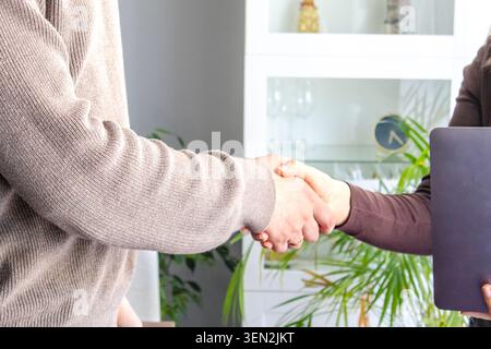 Stretta di mano tra due persone all'interno dell'ufficio domestico. Accordo commerciale, accordo di successo, fiducia, cooperazione e concetto di riunione di partnership Foto Stock