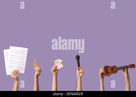 Mani che reggono spartiti musicali, tacca degli alti, portafoglio con denaro, microfono e ukulele su sfondo viola Foto Stock
