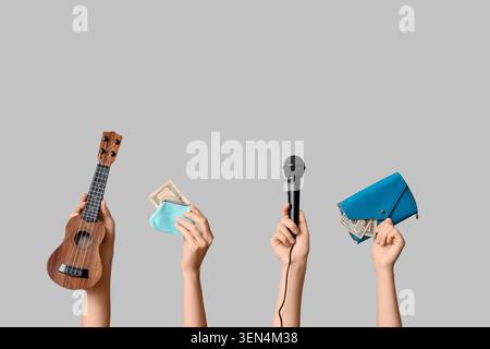 Mani che tengono in mano microfono ukulele e portafogli con soldi intrattenimento e successo finanziario Concept guadagni creativi di carriera Foto Stock