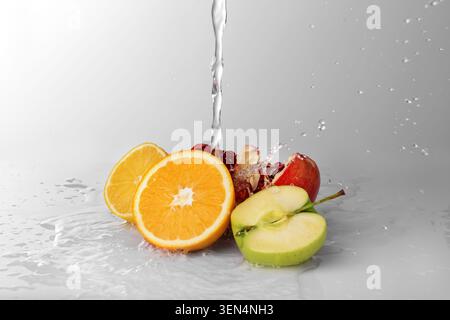 Agrumi freschi, arancio, limone, melograno e mele verdi con acqua spruzzata, cibo sano e rinfresco, ingredienti naturali e un vib pulito Foto Stock