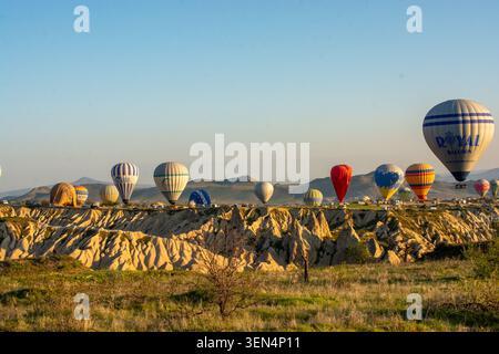 Vista panoramica mattutina delle colorate mongolfiere che si innalzano sul paesaggio unico della Cappadocia, la Turchia. Foto Stock