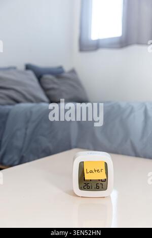 Adesivo con testo mai troppo tardi in sveglia sullo sfondo del letto da camera, concetto di scegliere la salute mentale e procrastinare per più tardi Foto Stock