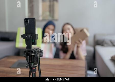 Smartphone su treppiede con persone sfocate in salotto Foto Stock