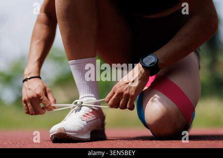 Atleta che si prepara per una corsa legando scarpe all'aperto in pista Foto Stock