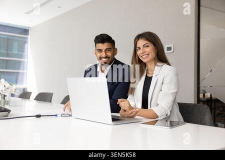 Colleghi multinazionali seduti alla moderna scrivania con computer portatile Foto Stock
