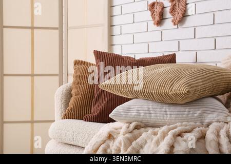 Interni accoglienti con cuscini in velluto a coste e soffice coperta su un comodo divano, arredi moderni del soggiorno Foto Stock