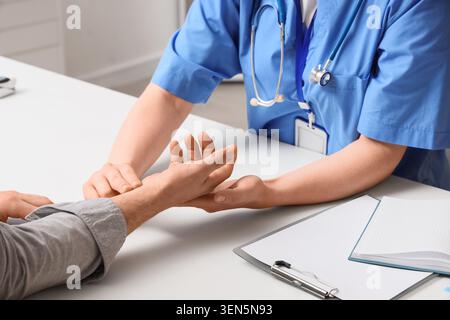 Medico che controlla il polso del paziente, l'esame sanitario, il monitoraggio dei segni vitali, la consultazione del medico, la valutazione dello stato di salute Foto Stock