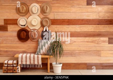 Interni eleganti con pareti in legno, panca, piante in vaso e una collezione di cappelli per un arredamento moderno Foto Stock
