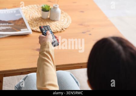 Persona che utilizza il telecomando per l'Home Entertainment, il tempo libero e il relax, tecnologia moderna per l'utilizzo dei contenuti multimediali Foto Stock