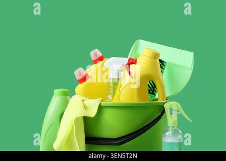 Secchio per forniture per la pulizia domestica con detergenti, spray, pennelli e panni in microfibra su sfondo verde Foto Stock
